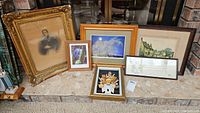 All six framed wall art pieces displayed together on a step, showing variety of art and frames.