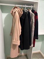 Four women's jackets and long coat hanging in a closet, showing the various styles and colors.