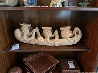 Front view of the wood sculpture showing six figures in a boat holding paddles.