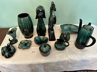 Blue Mountain Pottery assortment on white cloth showing variety of shapes and sizes with green-black glaze.