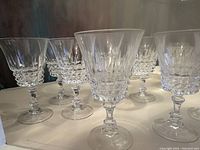 Front view of several crystal wine glasses showing the detailed cut pattern on the bowl and ornate faceted stems.