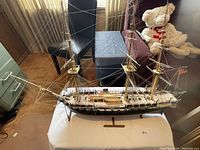 Side view of the large model sailing ship on its wooden stand showing the hull, rigging, and deck details.