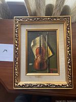 Full framed painting showing the violin hanging with part of the room shown behind it