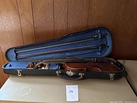 Hard shell violin case open, containing violin and two bows