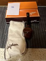 Vintage Brigham tobacco pipe resting on its original branded box with pouch nearby.