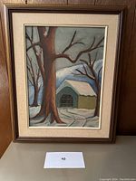 Framed oil painting on board showing a large bare tree, small green shed, snow and leafless trees in background.