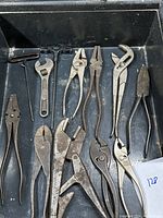 Overview photo showing 12 assorted vintage pliers and wrenches in a black tray, various sizes and types, all showing signs of age and use.