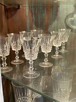 Eight clear crystal wine glasses arranged on a shelf, showing the full set and shape.