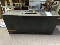 Closed antique wooden toolbox with visible wear, black painted finish, and metal handle on top.