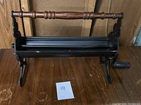 Full side view of old hand press showing the wooden handle, metal black frame, and stable base.