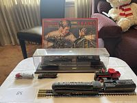 Photo showing the full set on a table with the poster in the background, including locomotives, flatbed car, and display case.