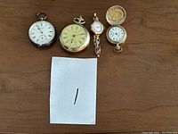 Overview of all four timepieces: three pocket watches and one wristwatch.