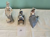 Photo of lot showing three figurines: standing woman with basket, two children on sled, seated woman with bird