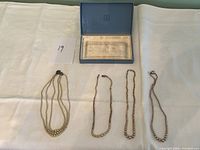 Photo showing three pearl necklaces laid flat with original blue Birks box with lid open.