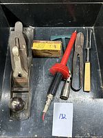 Top view of the lot showing Stanley hand plane, planer blades box, red soldering/hot air tool, metal pliers and forked tool inside a black tray