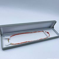 Necklace in a grey lined storage box, showing the full length and overall color and condition.