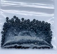 Clear resealable plastic pouch containing numerous small black faceted beads.