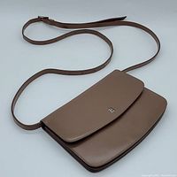 Front view of bag laid flat showing brown leather exterior and adjustable strap