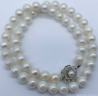 Coiled view of pearl necklace with floral clasp visible