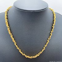 Front view of the Balmain gold plated necklace displayed on a black bust stand showing the twisted rope and oval link texture.