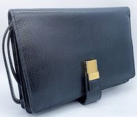 Front angled view of the black leather clutch showing the textured leather and gold-tone front clasp with the wrist strap.