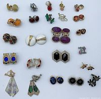 Top-down photo showing all 20 pairs of assorted vintage clip-on earrings arranged flat on a white surface with diverse styles and colors visible.