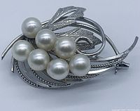 Front angle view of silver brooch featuring six white cultured Akoya pearls with leaf design