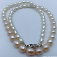 Close-up photo showing graduated oval pearls and silver tone barrel clasp of the necklace.