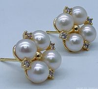 Close-up three-quarter view showing four pearls and clear stones set in gold-tone metal