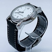 Side view of the Mercedes Benz wristwatch showing the silver-tone case, white dial with Arabic numerals, and black leather strap with white stitching.