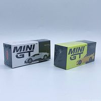 Two Mini GT diecast model boxes sealed in plastic wrap, one white and gray with Bugatti Centodieci, the other green and black with yellow sports car