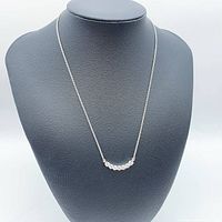 Full view of necklace on black display bust showing the length of chain and the pendant with seven moissanite stones.