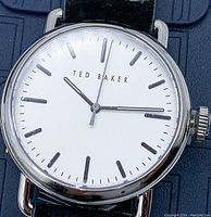 Close-up of the white dial showing the Ted Baker branding and black hour markers.