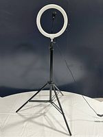 LED ring light on an adjustable tripod stand, powered off, showing front and stand arrangement