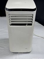 Front view of Arctic King portable air conditioner showing white body, digital display panel, and air output louvers.