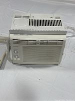 Front view of a white Frigidaire FFRA051WAE window-mounted air conditioner showing vent grille and manual control dials for temperature and mode.