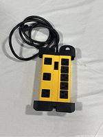 Top view of Apollo power bar showing yellow body with 8 black outlets and attached power cord coiled on top.