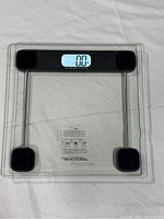 Top view of digital bathroom scale showing glass platform with black digital display reading 0.0.