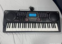 Full frontal view of the Casio CTK-631 keyboard showing the 61 keys, dual speakers, and backlit LCD screen with power cable coiled behind.