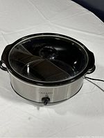Photo of Crock-Pot Classic Original Slow Cooker with glass lid on, showing stainless steel outer casing and black handles.