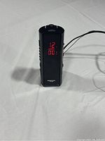 Front view of black digital alarm clock with red LED time display showing 12:00.
