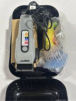 Electric hair clipper with attached cord, color-coded size comb guide, and a variety of guide combs and accessories in a black plastic tray