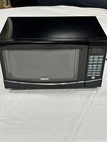 Front view of black RCA microwave oven showing control panel and door with RCA logo.