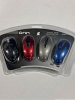 Front view of the closed plastic package containing four Onn optical mice in black, red, silver, and blue.