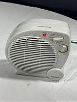 Front angle photo of Pelonis fan-forced heater showing control knobs, power light, and brand logo.