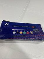 Blue box with visible brand 'MINGLE' showing the pressure washer wand extension and colored nozzle tips inside plastic packaging, displayed on white cloth background.