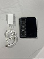 Samsung phone with slide-out keyboard, charger, and USB cable laid on surface.