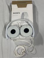 Sony MDR-ZX110 white over-ear headphones on top of their original box with cable coiled.
