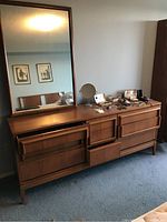 Front view of the wooden dresser with attached mirror, drawers visible with some open.