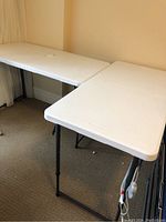 Two white Lifetime folding tables set side by side, showing full top surface and legs.